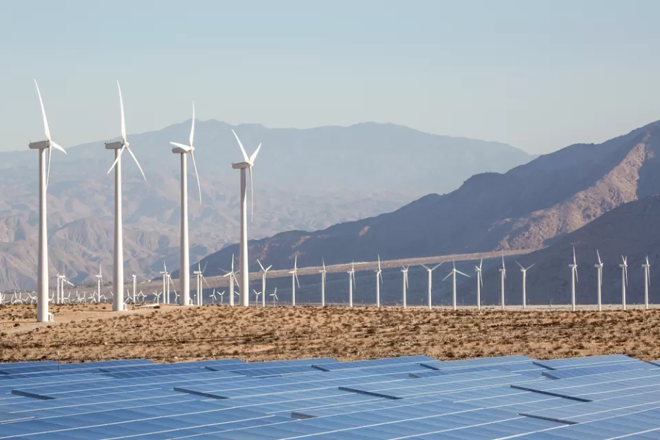 Wind turbines and solar panels against a backdrop of mountains in the Mojave Desert near Palm Springs, California